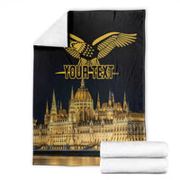 Black folded blanket with gold bird emblem and Budapest skyline, with towels