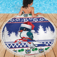 Round blue beach blanket on wood deck, fringed edge with Santa-hat bird design