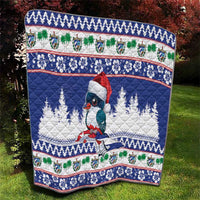Blue quilt with bird motif, white pine trees, and patterned holiday band