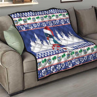 Blue quilt blanket on sofa with bird, pine trees, and holiday patterned border