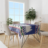 Blue Christmas tablecloth draped over table, featuring tree silhouettes and patterned trim