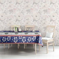 Blue Christmas tablecloth on table with tree and floral motifs, red trim along edge