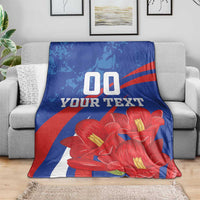Custom lapageria blanket draped over couch; blue/red/white with red flowers and '00 YOUR TEXT'.