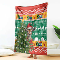 Christmas blanket draped over bed, green and red pattern with springbok and zigzag trim