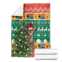 Folded Christmas blanket with green and red springbok holiday print and matching white towels