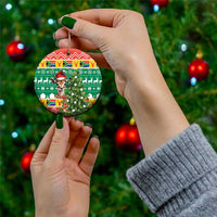 Round ceramic Christmas ornament held with gold string; springbok in hat on green festive design