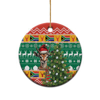 Round ceramic Christmas ornament with springbok head in red hat, green, red, and white patterns