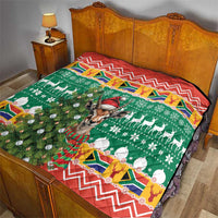 Christmas quilt blanket on bed: green tree pattern with zigzag red border and springbok center