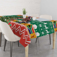 Christmas tablecloth draped over dining table, green and red with chevron and animal motifs