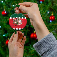 Hand holding a ceramic round Christmas ornament with reindeer floral design on red plaid