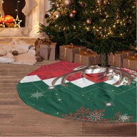 Round Christmas tree skirt on floor, green and red design with deer and pine motifs