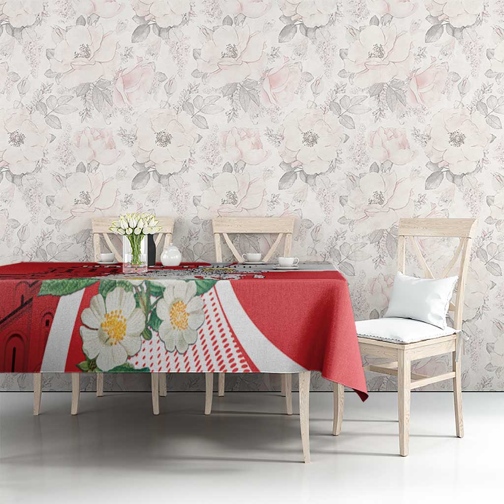 Red tablecloth with floral and church-style illustration and white trim on dining set