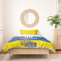 Bedding set on wooden bed with blue-and-yellow comforter; "00 YOUR TEXT" statue design.
