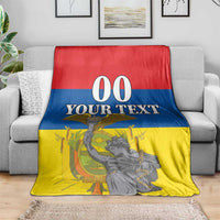 Ecuador Independence Day blanket on sofa, red blue yellow with "00 YOUR TEXT" and monument figure.