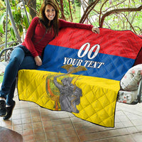 Large red, blue, and yellow quilt with “00 YOUR TEXT” and monument artwork, laid on patio.