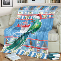 Blue Christmas blanket on sofa with green bird in Santa hat and Feliz Navidad text