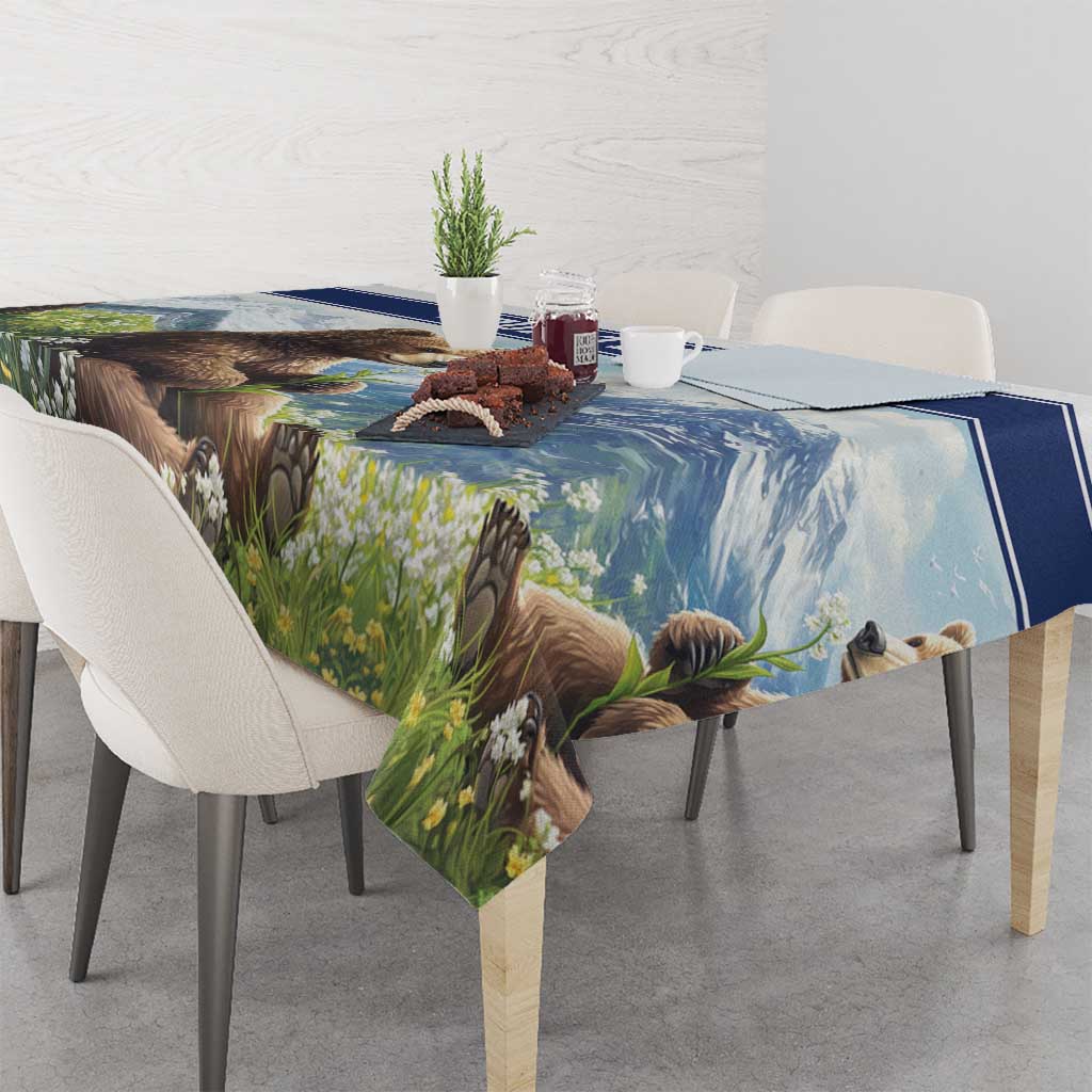 Tablecloth with blue-trimmed bear and meadow flowers print, draped over dining table