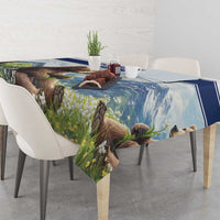 Tablecloth with blue-trimmed bear and meadow flowers print, draped over dining table