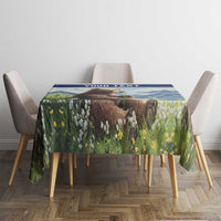 Personalized tablecloth with blue border, bear in green meadow, on dining table