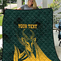 Folded green quilt showing yellow springbok graphic under customizable text