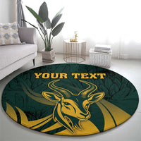 Round green springbok carpet with gold emblem, leafy design, and centered "YOUR TEXT"