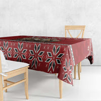 Red tablecloth featuring dark geometric snowflake design with draped corner