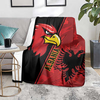 Red and black eagle emblem grunge pattern blanket folded over gray couch arm