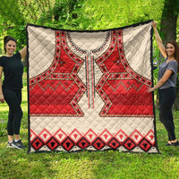 Beige quilt with red eagle motif, black accents, and red diamond pattern border on grass