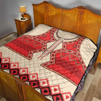 Beige quilt blanket with red eagle motif and geometric bands on bed