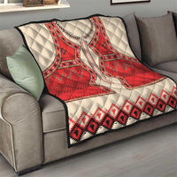 Beige quilt with red eagle motif and southwestern geometric pattern, folded on sofa