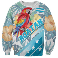 Unisex tropical sweatshirt with red-blue macaw, hibiscus, teal leaf print, diagonal Roatan text