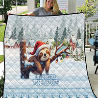 Blue quilt with quilted pattern and smiling sloth in red Santa hat with trees