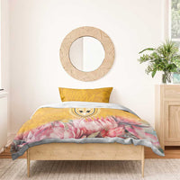 Yellow duvet cover with pink protea floral motif and central emblem, styled on light wood bed