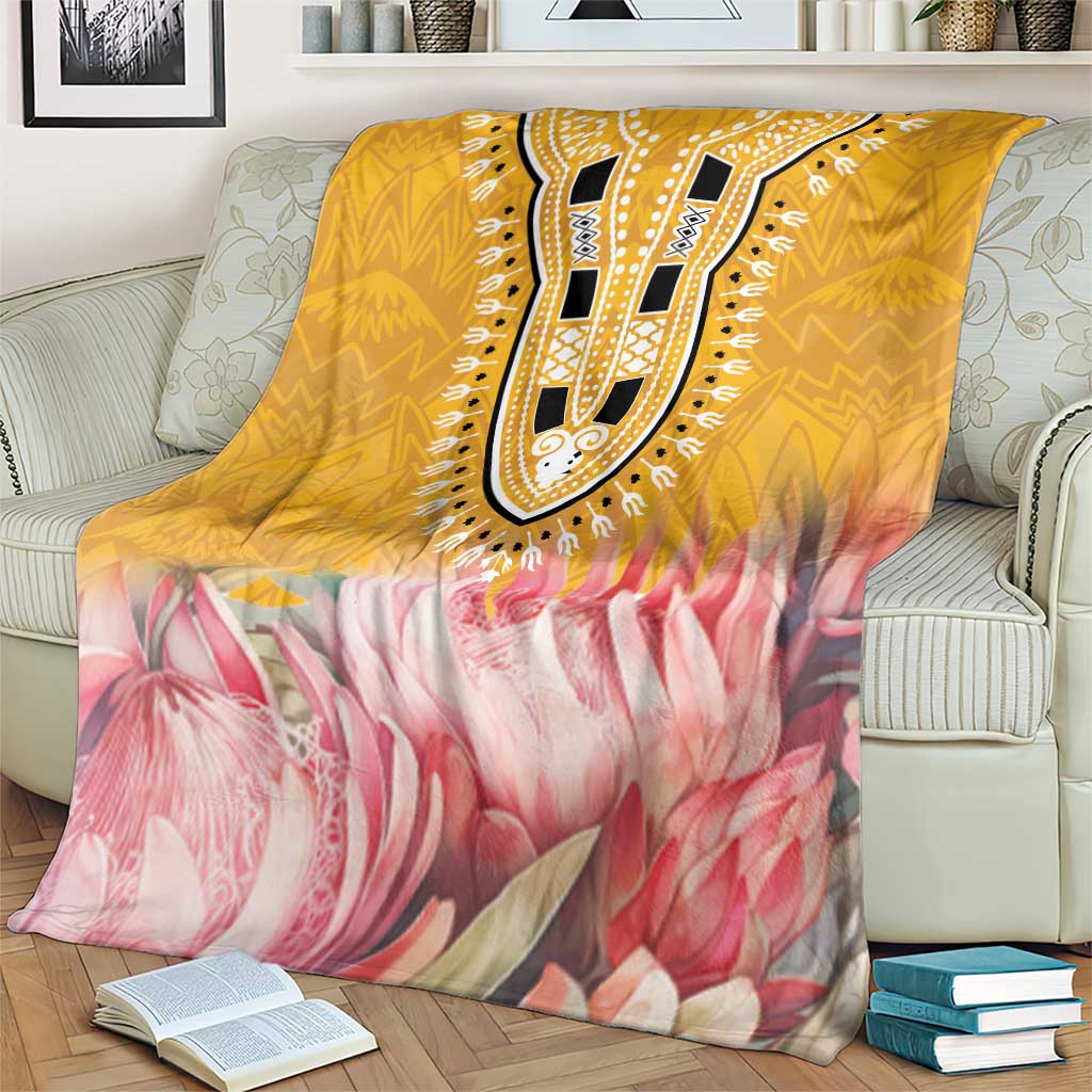 King-size blanket with yellow pattern band and pink protea blooms over armchair