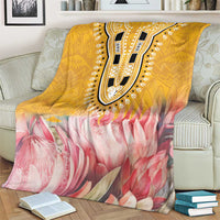 King-size blanket with yellow pattern band and pink protea blooms over armchair