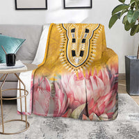 Yellow king blanket with dark ornamental face and pink protea floral print on sofa