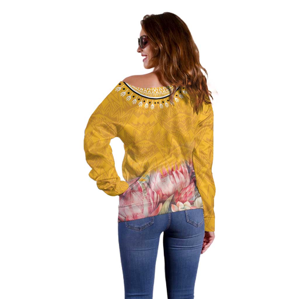 Yellow off-shoulder sweater viewed from back with geometric print and pink floral hem