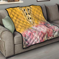 Yellow quilt folded on a sofa, featuring pink floral print and dashiki-style central motif