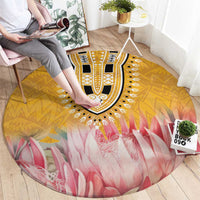 Round rug on hardwood floor with yellow medallion and pink petal-like pattern