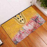 Yellow rubber doormat with black-and-white medallion and pink floral design in a corner