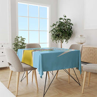 Blue tablecloth with coat of arms-style crest print on dining table with chairs.