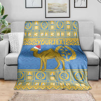 Blue throw blanket with camel graphic, Santa hat, and yellow patterned stripes on sofa