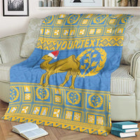 Blue blanket with camel graphic, Santa hat, and yellow patterned border over a couch