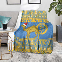 Blue camel-themed throw blanket with Santa hat, gold frame pattern, draped on a chair