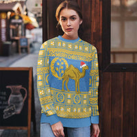 Light blue ugly Christmas sweater with gold pattern, camel, pine branches, and 'MERRY CHRISTMAS'