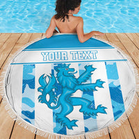 Round blue beach blanket with fringe edge, dragon graphic and 'YOUR TEXT' on wooden deck