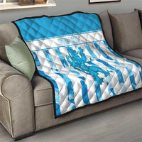 Blue and white quilt draped on sofa, striped pattern with dragon emblem and custom text