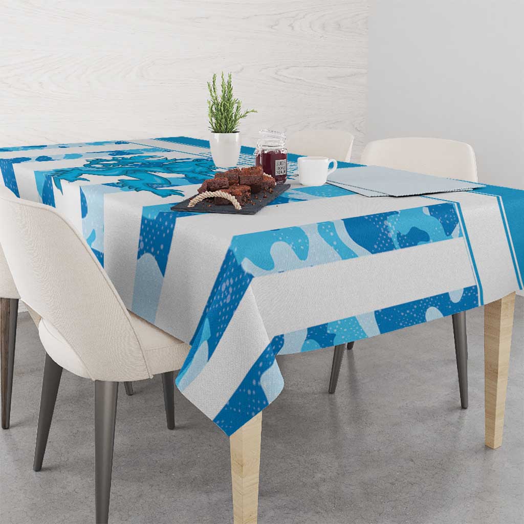 Blue patterned tablecloth on dining table with cups, plate, and flowers