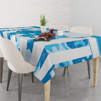 Blue patterned tablecloth on dining table with cups, plate, and flowers