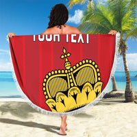 Red circular football beach blanket with yellow crest and white fringe, held outdoors